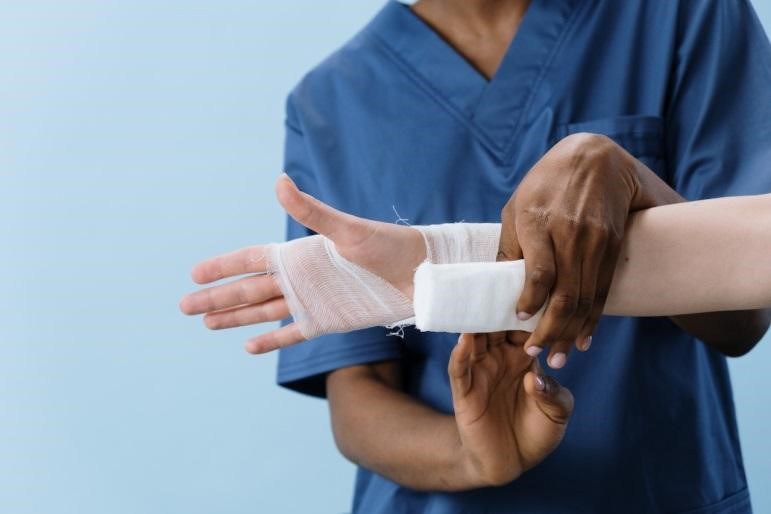 A healthcare professional bandaging a hand
