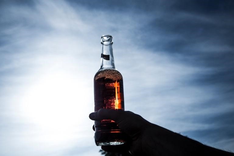 A person holding a glass beer bottle