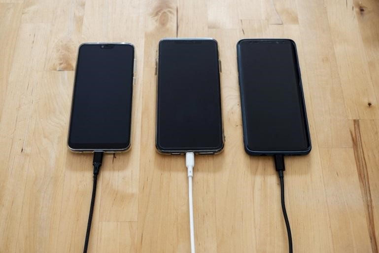 Three black Android smartphones charging